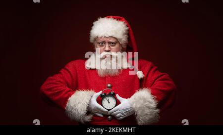 Der weihnachtsmann hält den Wecker fast um Mitternacht Stockfoto