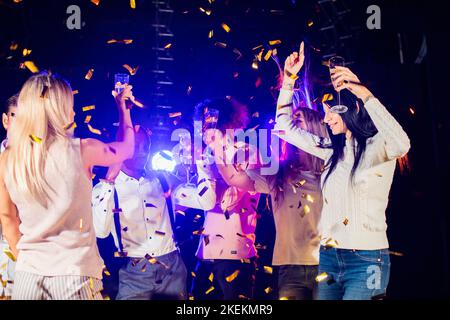 Eine Gruppe von schönen jungen Leuten, die mit Sektflöten feiern und glücklich aussehen. Die Party im neuen Jahr Stockfoto