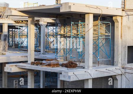 Kran und Gebäude im Bau gegen blauen Himmel am Seeufer. Stadtlandschaft Stockfoto