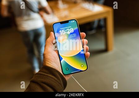Paris, Frankreich - 28. Okt 2022: Männliche Hand hält neues leistungsfähiges iPhone 14 neues Smartphone von Apple Computers - Bunte Tapete Stockfoto