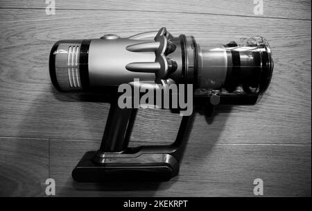 Direkt über Ansicht moderner kabelloser Staubsauger leistungsstarker Akku Bunte zyklonische Staubsammlung - Holzparkettboden - Schwarz-Weiß-Schwarzweißfoto Stockfoto