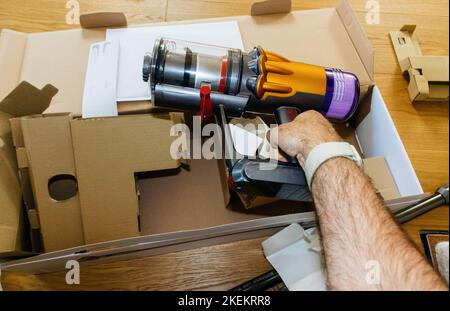 Paris, Frankreich - Jul 4, 2022: Mann hält beim Auspacken aus der Box nehmen neuer moderner kabelloser Dyson V12 Detect Slim Absolute Staubsauger leistungsstarke kabellose, farbenfrohe, zyklonische Staubsammlung Stockfoto