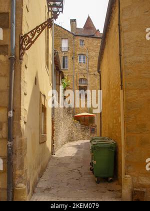 Gasse mit grünen Wheelie bins der malerischen, mittelalterlichen Stadt Sarlat-la-Canéda in Frankreich Stockfoto