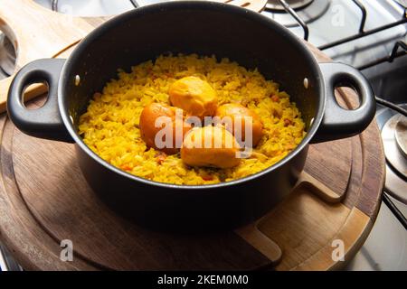 Goiânia, Goias, Brasilien – 13. November 2022: Eine schwarze Pfanne mit Reis und Pequi auf einem Holzbrett. Ein typisch brasilianisches Gericht. Stockfoto