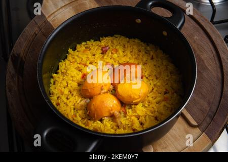 Goiânia, Goias, Brasilien – 13. November 2022: Eine schwarze Pfanne mit Reis und Pequi auf einem Holzbrett. Ein typisch brasilianisches Gericht. Stockfoto