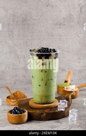 Boba oder Tapioka Perlen ist taiwan Bubble Milch Tee in Kunststoff-Tasse mit Matcha-Geschmack auf Textur Hintergrund, Sommer Erfrischung. Stockfoto