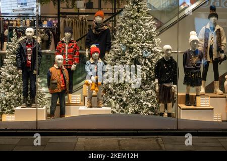 Winterkleidung für Kinder, die in einem Schaufenster mit Weihnachtsbäumen in Liverpool ausgestellt ist Stockfoto