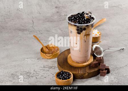 Boba oder Tapioka Perlen ist taiwan Bubble Milch Tee in Kunststoff-Tasse mit Kaffee-Geschmack auf Textur Hintergrund, Sommer Erfrischung. Stockfoto