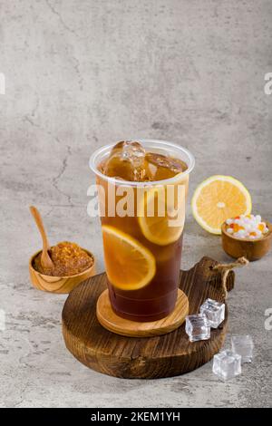 Süßer Limonadentee in Plastikbecher mit Eis auf Texturhintergrund, sommerliche Erfrischung. Stockfoto