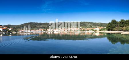 Panoramablick auf Veli Iz in Kroatien mit Booten, Häuser, Hügel im Hintergrund und einem klaren blauen Himmel Stockfoto