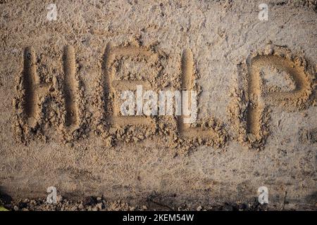 Hilfe. Inschrift in Buchstaben auf Sand. Blick von oben. Bitten Sie um Hilfe... Stockfoto