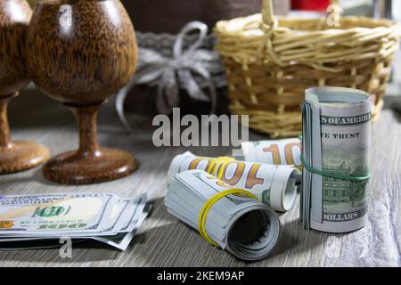 Nahaufnahme von zusammengerollten amerikanischen Dollar-Banknoten auf einem grauen Holztisch. Bank- und Finanzkonzept Stockfoto