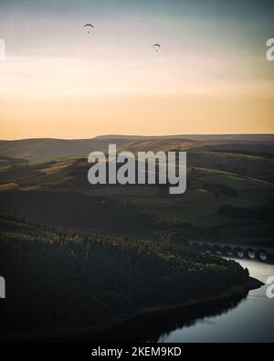 Gleitschirmflieger genießen den Sonnenuntergang über dem Ladybower Stausee vom Bamford Edge aus. Stockfoto