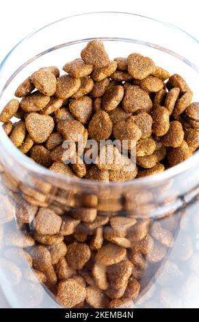 Trockenes Tierfutter in einem Glas Nahaufnahme auf weißem Hintergrund.auf grauem Hintergrund Stockfoto