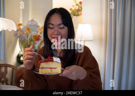 Frauen essen Kuchen zu Hause mit glücklichen Gesichtsausdruck. Stockfoto