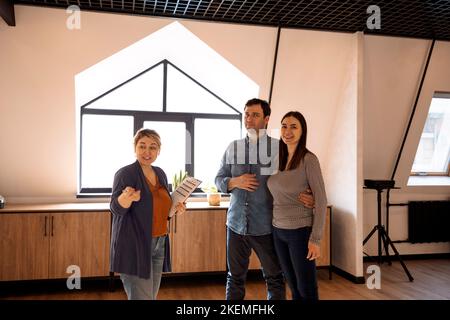 Immobilienmakler mit jungen Paar in neuer Wohnung. Manager realtor Advisor berät Paar über Vertragsbedingungen bei der Besprechung. Familie beteiligt Stockfoto