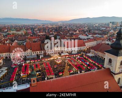 Landschaftsfotografie des Stadtzentrums von Sibiu mit der Weihnachtsmesse, aufgenommen von einer Drohne bei Sonnenuntergang mit dem Blitz der Stadt. Vogelperspektive über die Stadt Stockfoto