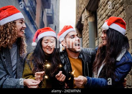 Fröhliche junge, vielfältige Menschen, die Spaß haben, am Weihnachtsabend mit bengalischen Feuer im Freien zu feiern - Fokus auf homosexuelles Transgender-Männergesicht Stockfoto