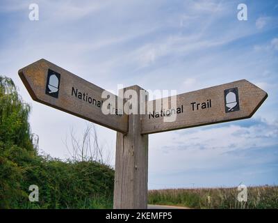 Ein verwitterter hölzerner Fingerpost weist den Weg auf den North Norfolk Coast Path. Stockfoto
