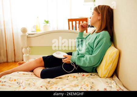 Teenager-Mädchen, das CD zeigt und Musik in ihrem Zimmer hört. Mädchen mit Retro-Spieler Stockfoto
