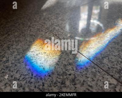 Regenbogen-Lichtbrechung auf grauem Granitboden Stockfoto