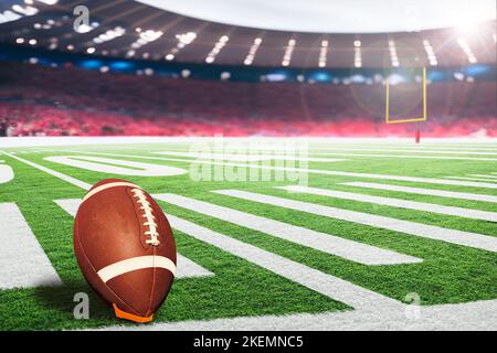 American Football Stadium mit Torpfosten und Ball auf Abschlag bereit für den Spielfeldtreffer. Konzentrieren Sie sich auf den Vordergrundball mit geringer Schärfentiefe im Hintergrund Stockfoto