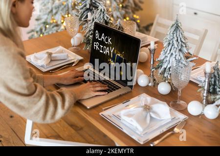 Black Friday Shopping-Konzept auf dem schwarzen Bildschirm des Laptops vor verschwommenem weihnachtslicht Hintergrund geschrieben Stockfoto