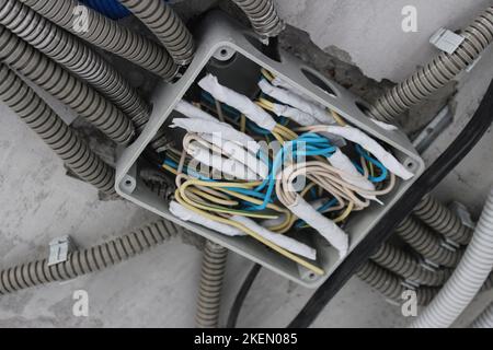 Verdrehen der elektrischen Leitungen im Anschlusskasten während der Installation der elektrischen Leitungen im Raum Stockfoto