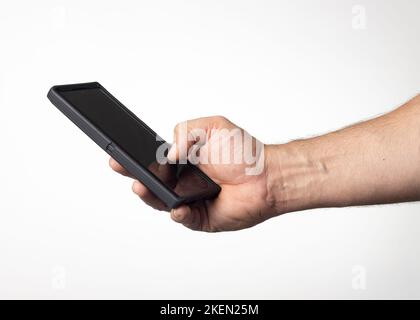 Hand und Arm eines Mannes, der ein Mobiltelefon mit einem schwarzen Bildschirm auf einem kernweißen Hintergrund hält. Stockfoto