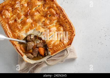 Englischer Rindersteak-Kuchen mit knusprigem Blätterteig in einer Backform Stockfoto