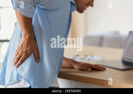 Mann, der starke Rückenschmerzen durch lange sitzende Arbeit am Computer im Büro hat. Schlechte Körperhaltung Stockfoto