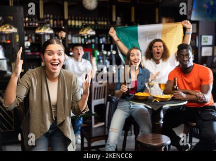 Junge Frau, die die Fußballmannschaft in der Bar unterstützt Stockfoto