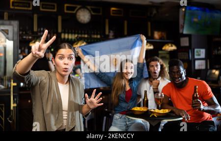 Junge Frau, die die Fußballmannschaft in der Bar unterstützt Stockfoto