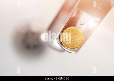 20-Cent-Münze auf einem Wasserhahn im Bad. Sparsamer Wasserverbrauch konzeptionelle Idee. Sparkonzept für Haushaltsbudgets. Stockfoto