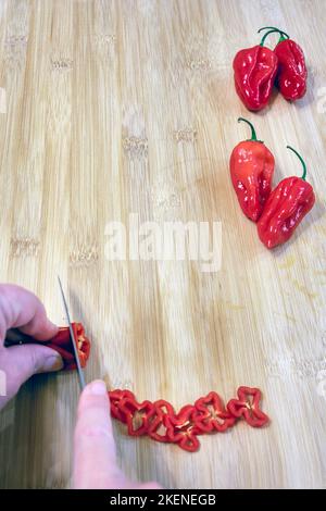 Capsicum chinense 'Scotch Bonnet' wird auf einem Holztisch geschnitten Stockfoto