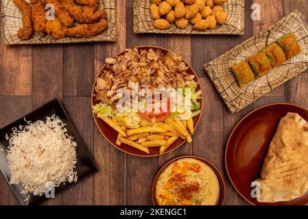 Set von Kebab-Restaurant-Speisen mit gemischtem Lamm- und Hühnerfleisch, Kroketten, Pilau-Reis, süßem Baklava, Hühnerpuffs Stockfoto