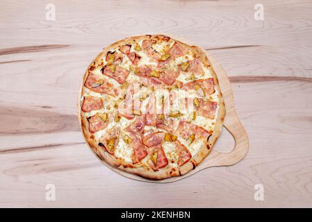 Pizza mit Karbonara-Rezept der Familie mit viel Mozzarella-Käse und yorkschinken auf einem ungelackierten Holztisch Stockfoto