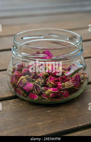 Durchsichtiges Glas gefüllt mit getrockneten Rosenknospen, um Tee zu machen Stockfoto