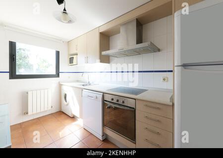 Küche mit glatten Möbeln aus Buchenholz und integrierten weißen und Edelstahl-Geräten Stockfoto