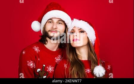 Junges Paar in Weihnachtspullover und Weihnachtsmützen. Frohes neues Jahr feiern. Frohe Feiertage. Stockfoto