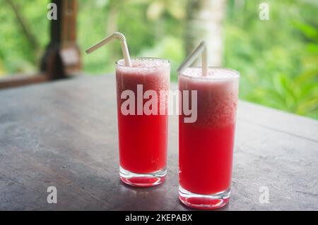 Zwei Gläser mit frischem Wassermelonensaft auf einem Holztisch in einer Villa in den Hügeln von Ceking, Ubud – Bali, Indonesien Stockfoto