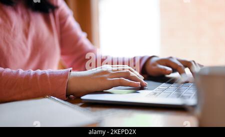 Nahaufnahme, Freiberuflerin oder Studentin, die auf der Laptop-Tastatur tippt, mit Notebook-Laptop-Computer im Café. Stockfoto