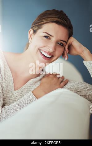 Manchmal musste man sich einfach ein wenig entspannen. Eine junge Frau, die sich zu Hause auf ihrem Sofa entspannt. Stockfoto