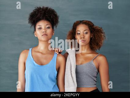 Fitness ist unser Hauptaugenmerk. Studioportrait von zwei jungen Frauen nach dem Yogakurs vor grauem Hintergrund. Stockfoto