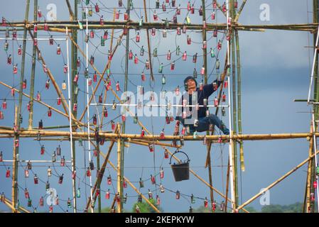 Asiatischer Mann bei der Arbeit auf Bambusgerüst, bereitet sich auf das Nakhon Phanom Boat Festival in Thailand vor. Stockfoto