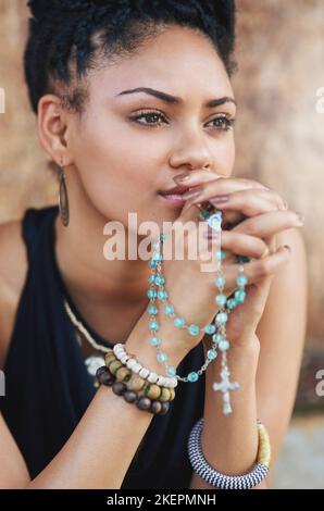 Es gibt immer Zeit zum Beten. Eine attraktive junge Frau, die mit ihrem Rosenkranz im Freien betet. Stockfoto