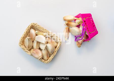 Knoblauchzehen in Miniaturkörben auf weißem, isoliertem Hintergrund Stockfoto