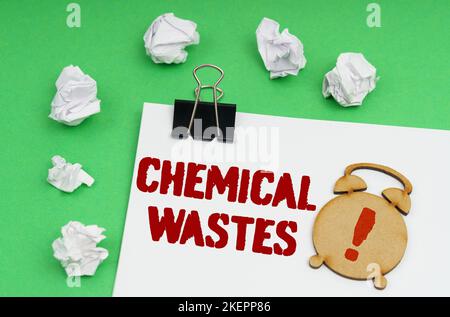 Umweltkonzept. Auf einem grünen Hintergrund befindet sich ein weißes Blatt, auf dem sich eine Figur eines Weckers und eine Aufschrift - Chemische Abfälle befindet Stockfoto