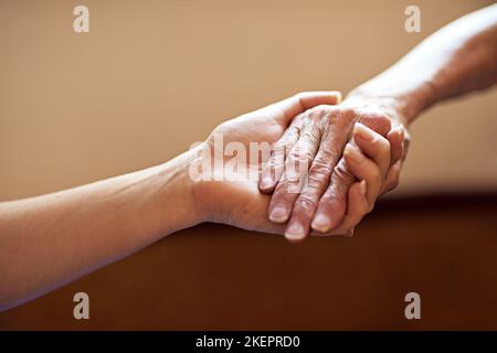 Ein einfacher Akt der Freundlichkeit kann die Welt bedeuten. Eine Person, die eine ältere Frau Hände hält. Stockfoto