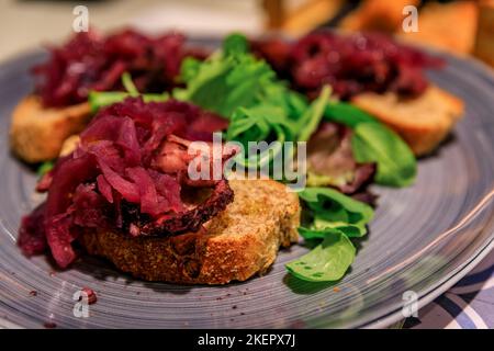 Frisch zubereitete Bruschetta mit gegrilltem Oktopus und eingelegten Zwiebeln in einem Restaurant in der Altstadt von Manarola in Cinque Terre am Mittelmeer, Italien Stockfoto